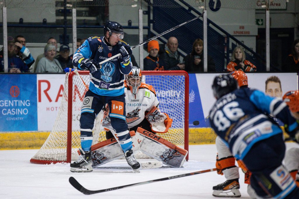 Mismash shoots the puck against Greenfield with Pelech providing a screen in front.